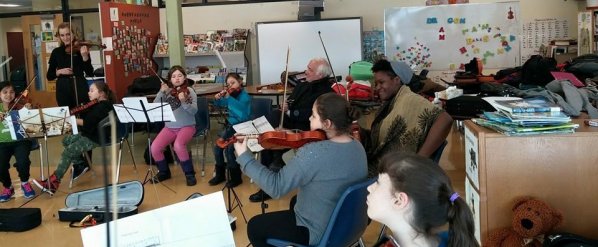 Musicians of the UNC Charlotte Chamber Orchestra collaborating with children at Kahnawake, Quebec. The gentleman in the center of the image is Ken Lambla, Dean of the College of Arts and Architecture at UNC Charlotte.
